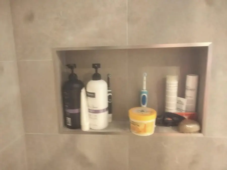 Styled shower niche with metal trim set into grey tile