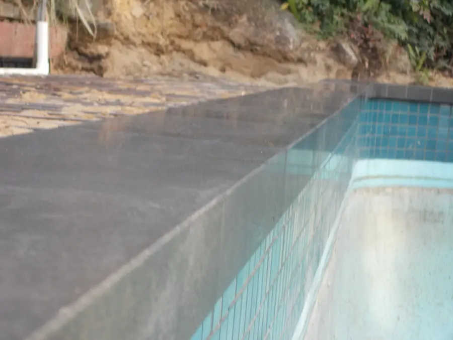 Finished pool coping in natural stone above blue pool mosaic