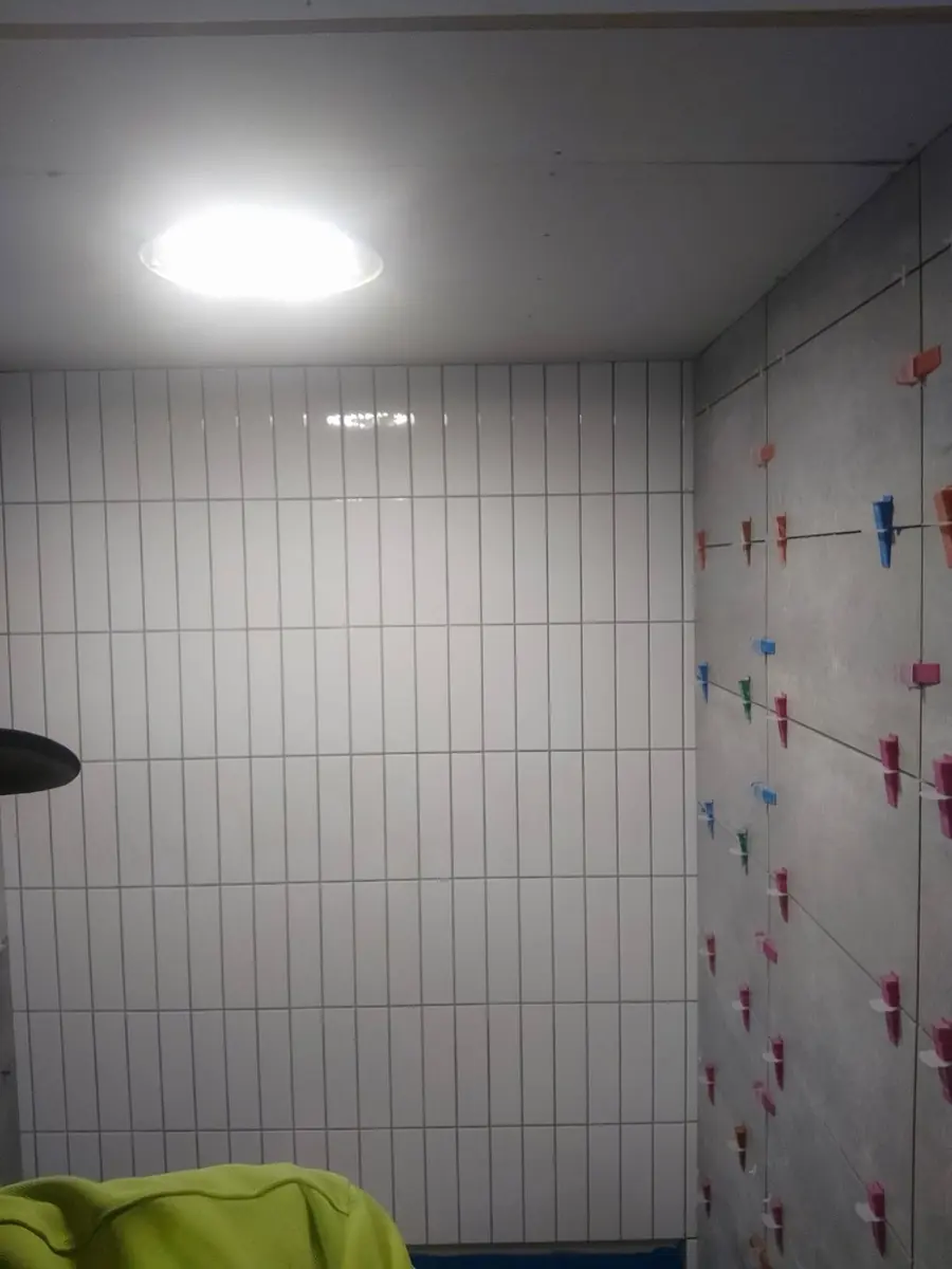 Wall tiles mid-install with levelling clips holding every joint flat